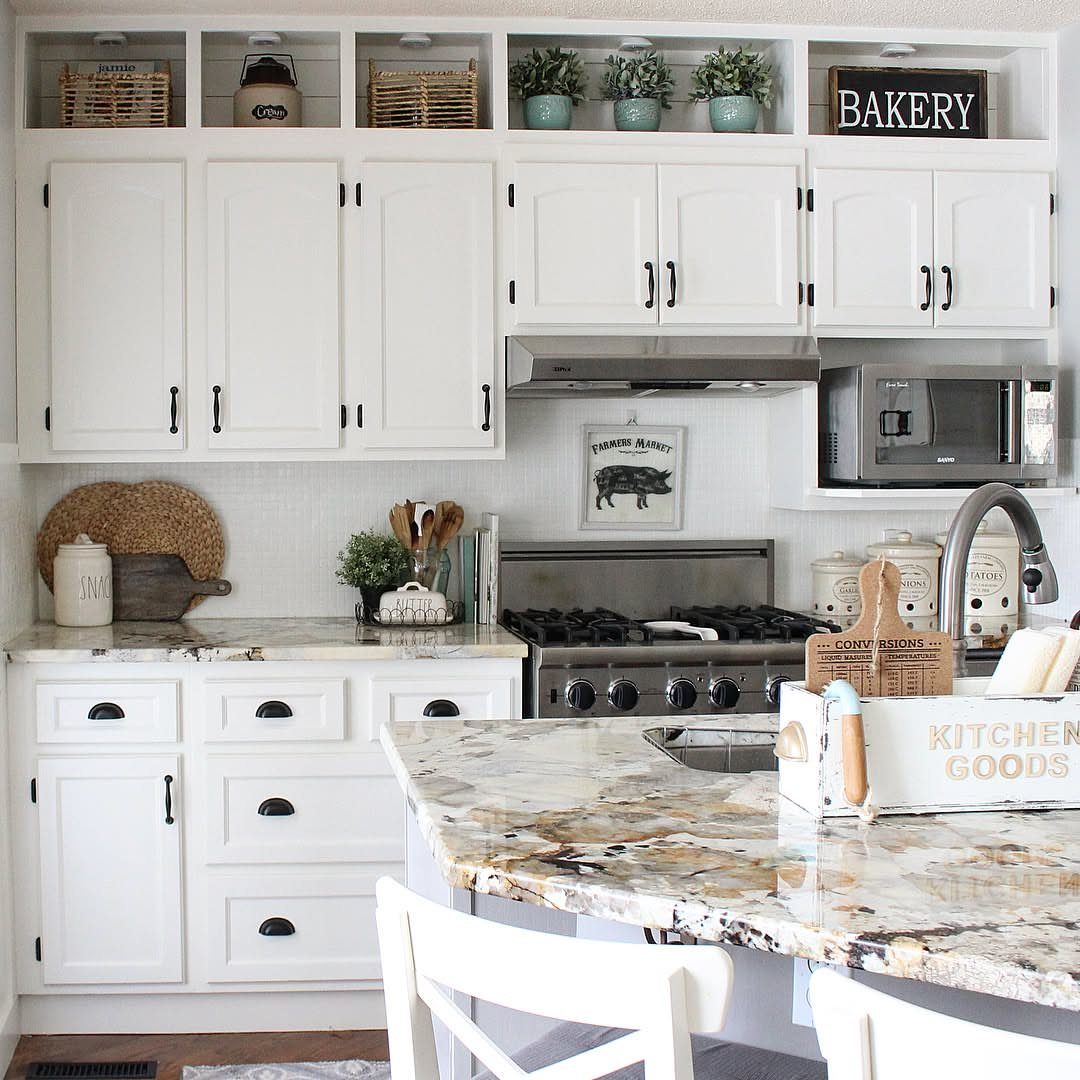 White kitchen cabinets with decorative baskets and plants displayed in the open cubbies above.