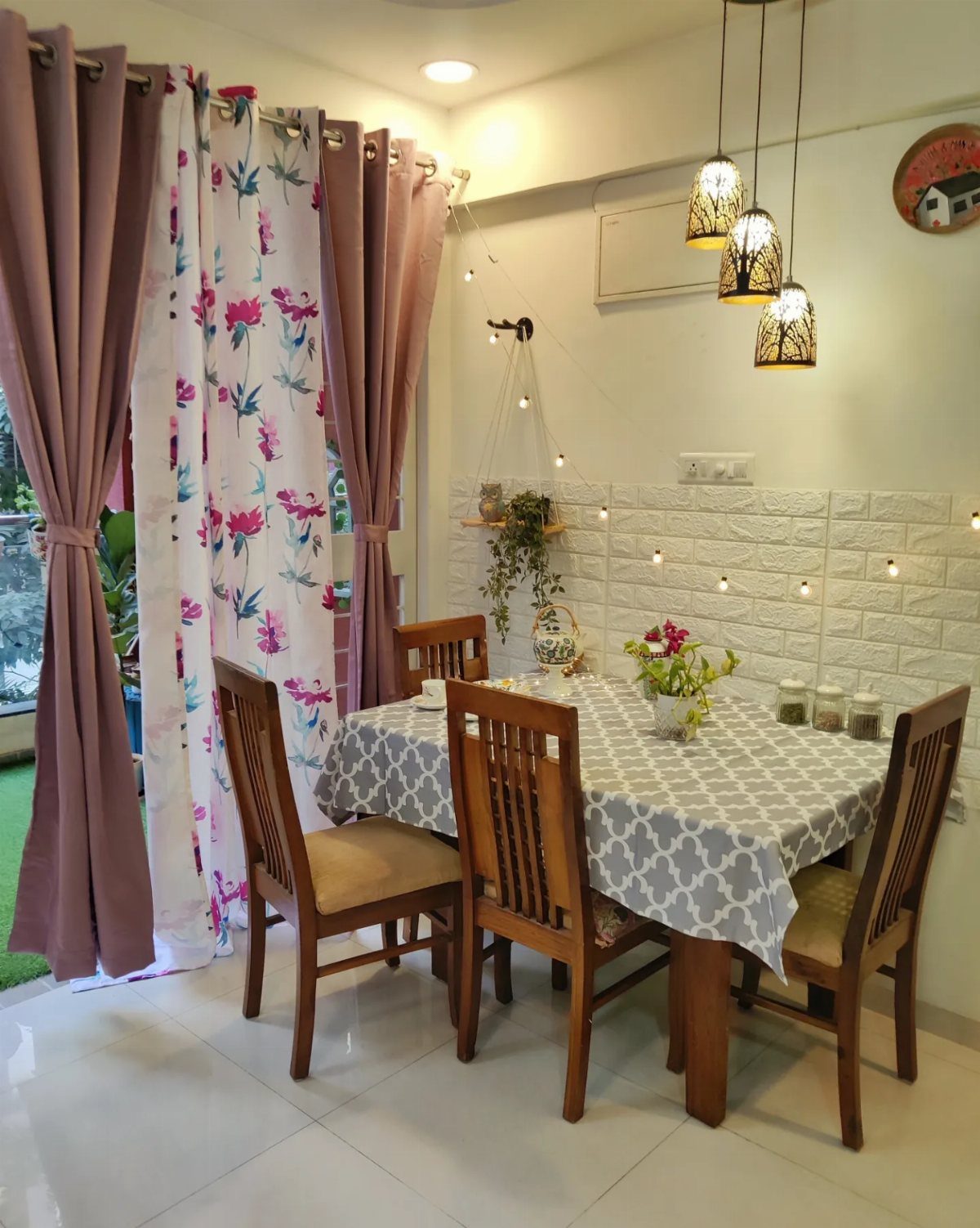 A wooden dining table set with a patterned cloth and chairs in a decorated room.