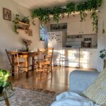 Wooden dining table and chairs set in a bright kitchen with hanging green vines.