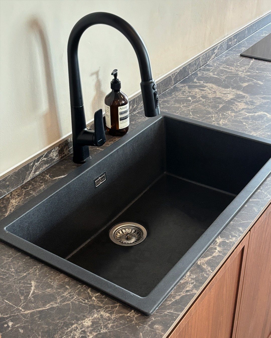 A matte black rectangular kitchen sink with a matching black faucet on a dark marble countertop.