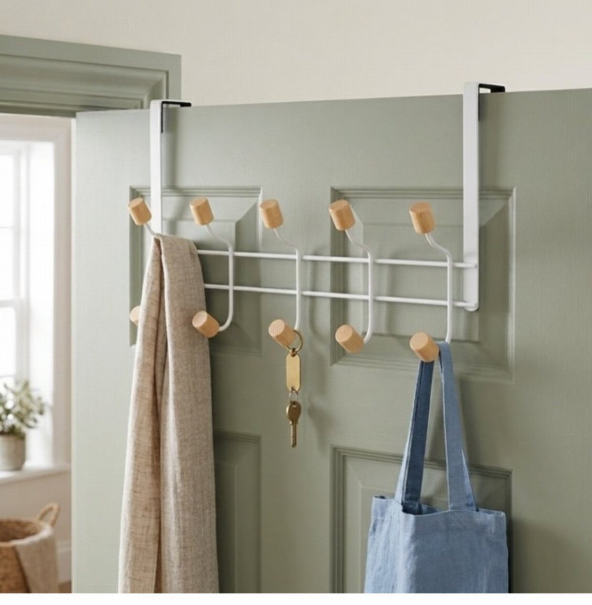 White over-the-door hook rack with wooden knobs holding a scarf, keys, and a blue tote bag.